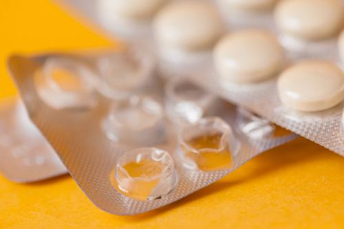 A closeup of a pack of Zantac pills on a yellow background.