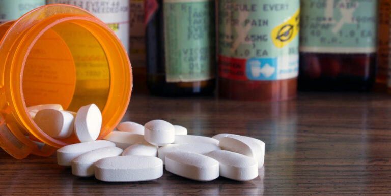 Opioids spilling out prescription bottle.