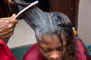 Hair Relaxer Lawsuit African American Black Woman getting hair relaxer or hair straightener treatment at the salon