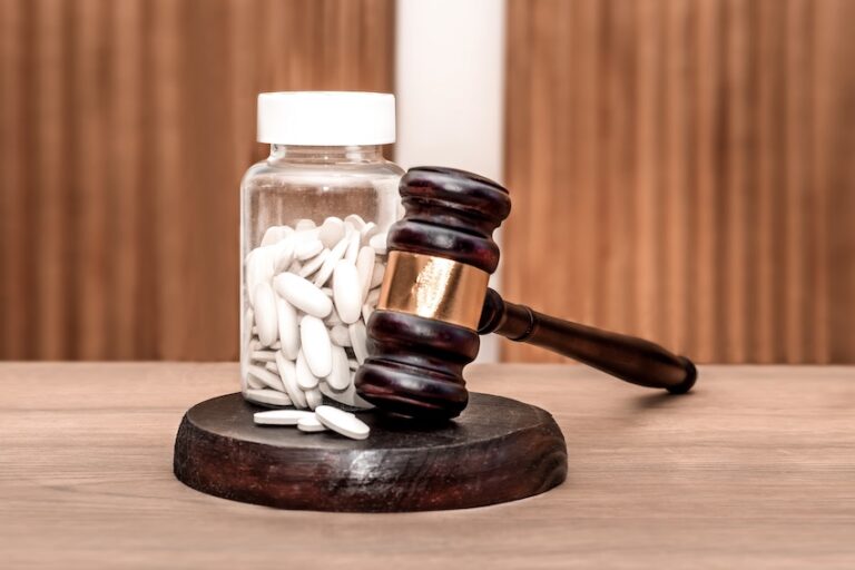 A gavel and a bottle of while pills represent an Oxbryta lawsuit.