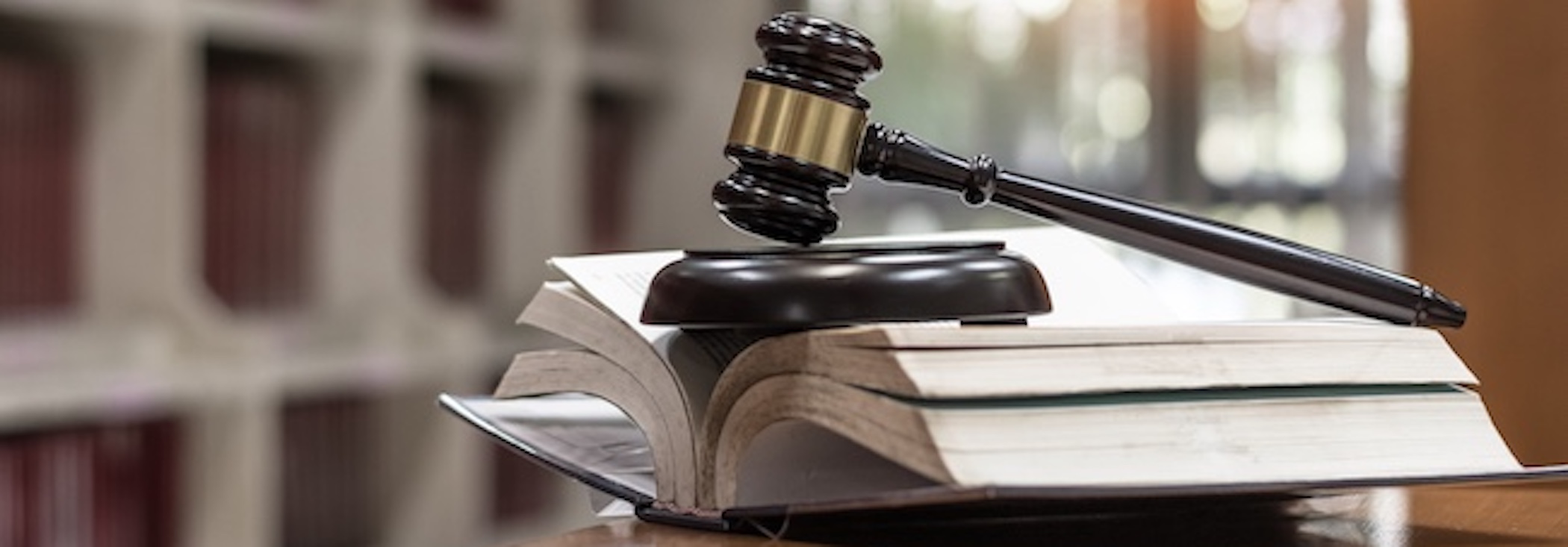 What Are Mass Tort Damages and Their Impact? A mass tort book opened with a gavel placed above it, on top of a desk, inside a library.