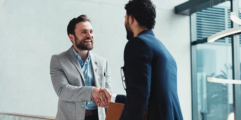 Understanding Defective Product Liability in Mass Tort Cases Handshake between two Caucasian males at a window in an office.