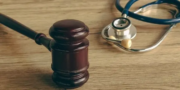 A judge's gavel next to a stethoscope on a wooden desk representing defective medical lawsuits and healthcare liability legal proceedings.