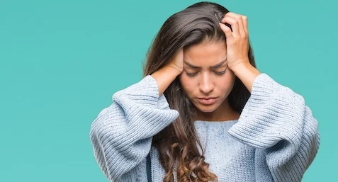 A woman is holding her head in distress, experiencing pain, representing victims in injury litigation seeking compensation for harmful products.