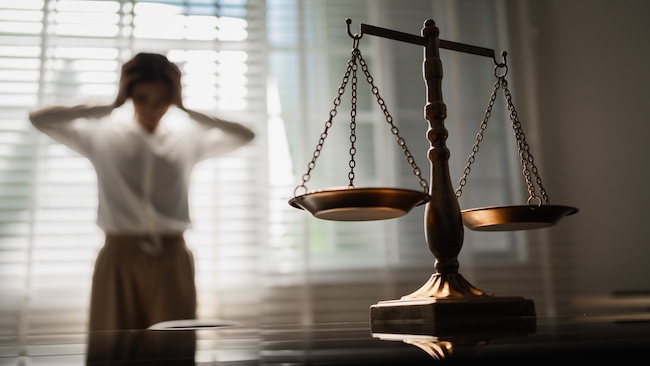 Scales of justice with a distressed woman in the background symbolizing mass tort claims involving multiple injured plaintiffs seeking compensation.