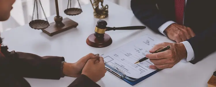 An attorney and a client are reviewing legal documents with a gavel and scales representing mass tort lawsuits against pharmaceutical companies.