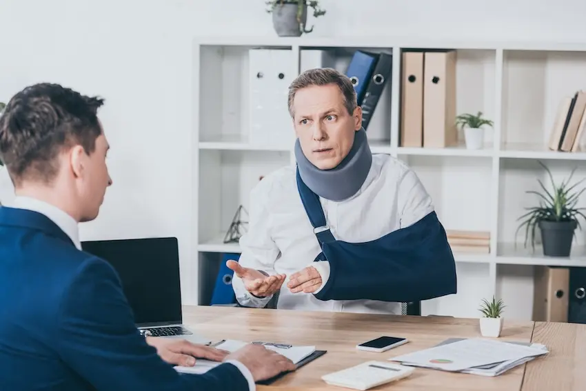 San Diego car accident lawyer consulting with an injured client in an office, reviewing documents and providing legal guidance.