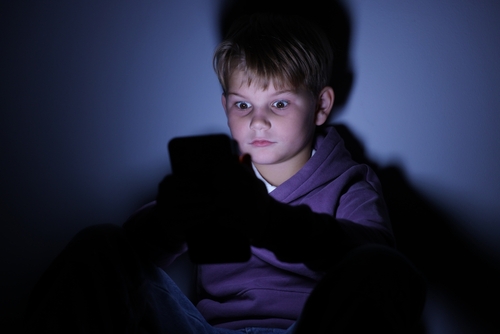 A child on a tablet in the dark to represent an addicition to social media to the point his parents will file a social media addiction lawsuit.