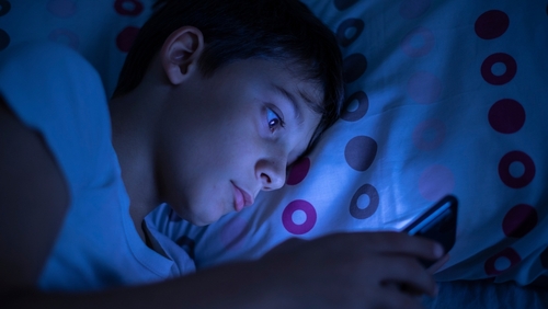 Kid on his phone at night represent an addicition to social media to a point where their parents will file a social media addiction lawsuit.