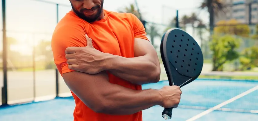 What Is Failure to Warn and Why Does It Matter in Mass Tort Cases? An African American male pickleball player in an orange shirt grips his shoulder in pain while holding a paddle on an outdoor court- reflecting the type of injury that can lead to a product liability claim when equipment manufacturers commit failure to warn about known risks of use within the USA.